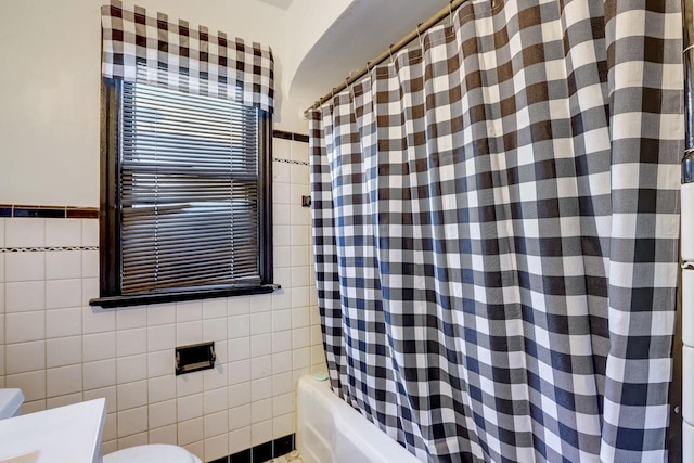 bathroom with toilet, shower / bathtub combination with curtain, and tile walls