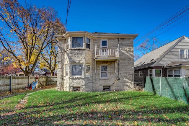 rear view of property with a balcony and a lawn