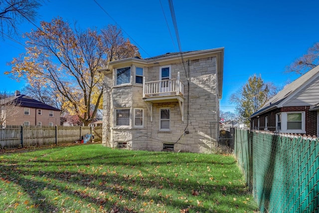 back of house with a balcony and a lawn