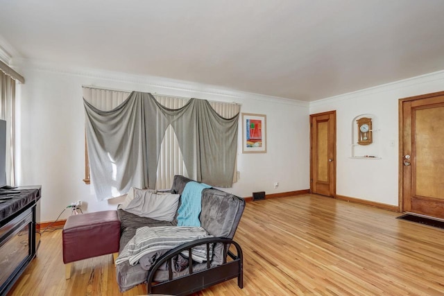 living area with ornamental molding and light hardwood / wood-style floors