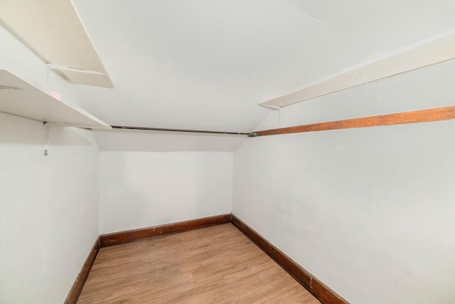 spacious closet with vaulted ceiling and light hardwood / wood-style flooring