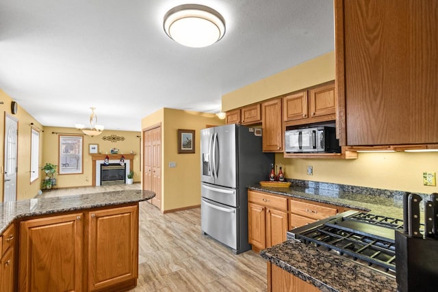 kitchen with kitchen peninsula, stainless steel refrigerator with ice dispenser, dark stone counters, an inviting chandelier, and light hardwood / wood-style flooring