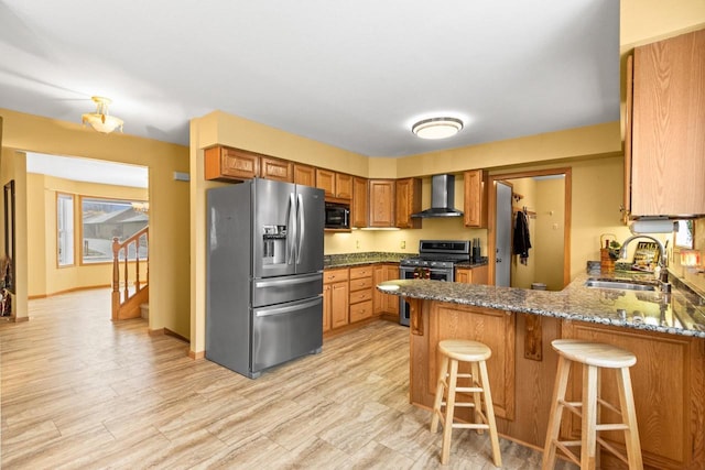 kitchen with sink, wall chimney exhaust hood, stone countertops, kitchen peninsula, and stainless steel appliances