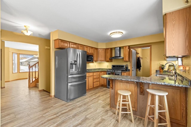 kitchen with sink, wall chimney range hood, kitchen peninsula, a breakfast bar, and appliances with stainless steel finishes