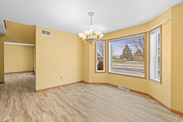 empty room featuring light hardwood / wood-style floors and a chandelier