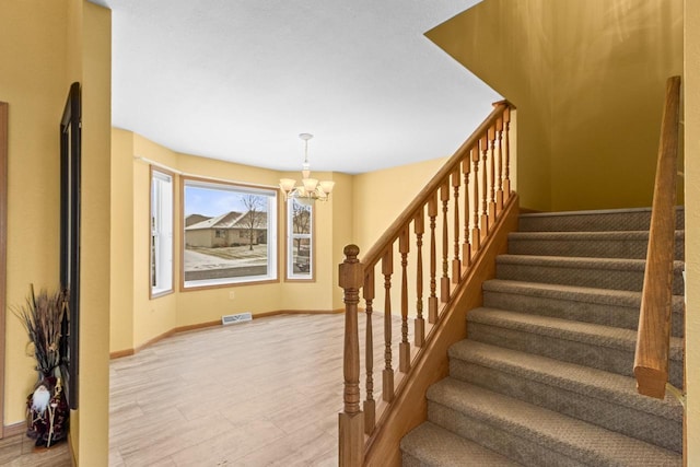 staircase with hardwood / wood-style floors and a chandelier