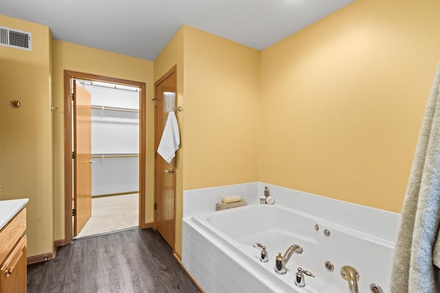 bathroom featuring tiled tub, hardwood / wood-style floors, and vanity