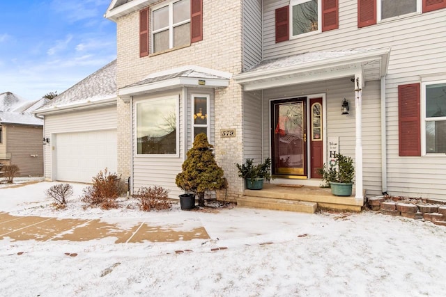 snow covered property entrance featuring a garage