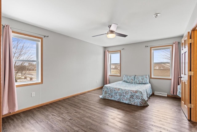 unfurnished bedroom featuring multiple windows, ceiling fan, and dark wood-type flooring