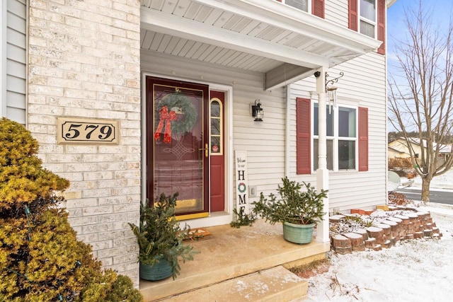 snow covered property entrance with covered porch