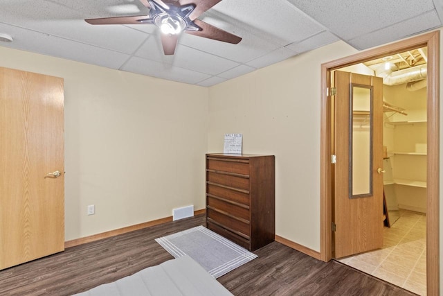 bedroom featuring a paneled ceiling, ceiling fan, hardwood / wood-style flooring, a spacious closet, and a closet