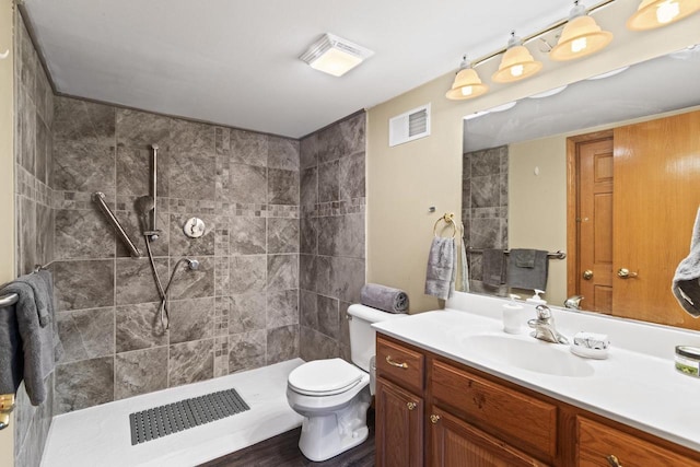 bathroom with vanity, toilet, and a tile shower