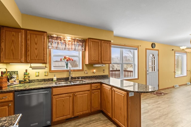 kitchen featuring an inviting chandelier, sink, stainless steel dishwasher, dark stone countertops, and kitchen peninsula