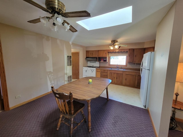 dining room with sink, ceiling fan, and a skylight