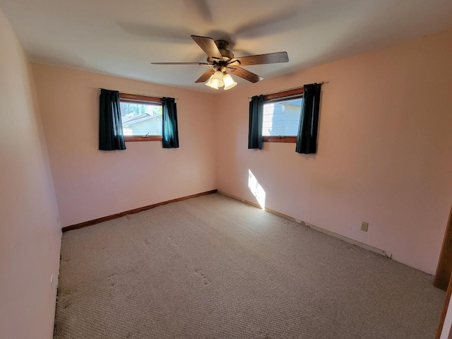 spare room with light carpet, ceiling fan, and a wealth of natural light