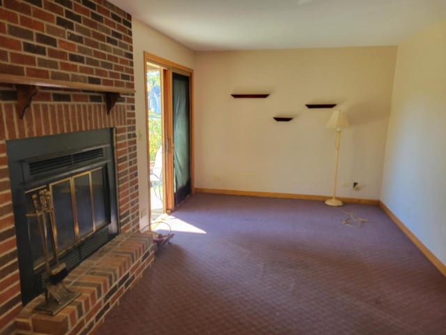 unfurnished living room featuring dark colored carpet and a brick fireplace