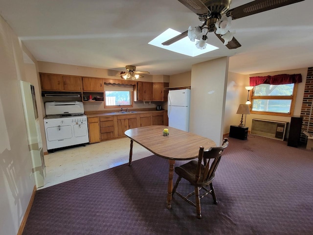 kitchen with white appliances, ceiling fan, a healthy amount of sunlight, and a skylight