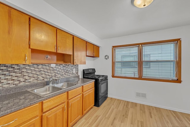 kitchen featuring backsplash, sink, light hardwood / wood-style flooring, and gas stove