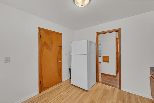 unfurnished bedroom with light hardwood / wood-style flooring and white fridge