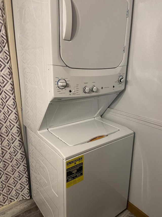 laundry area with stacked washer / dryer and wood-type flooring