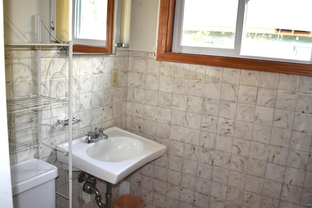 bathroom with toilet and tile walls