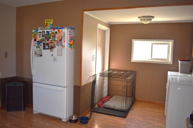 interior space featuring washing machine and dryer, hardwood / wood-style flooring, white fridge, and crown molding