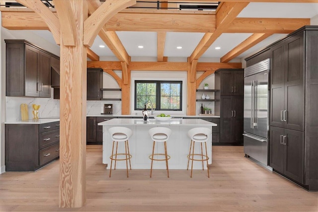 10823 Pleasant Valley Rd, Cedarburg, WI 53012 - kitchen with stainless steel built in refrigerator, open shelves, a breakfast bar area, beam ceiling, and light countertops
