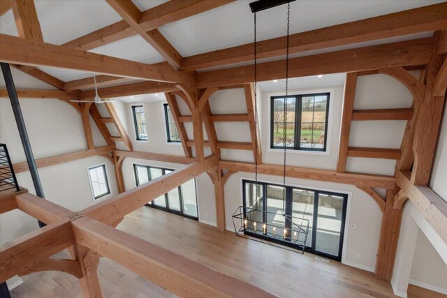 interior space with wood finished floors, beam ceiling, and baseboards