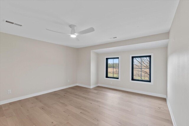 unfurnished room featuring visible vents, light wood-style flooring, and baseboards