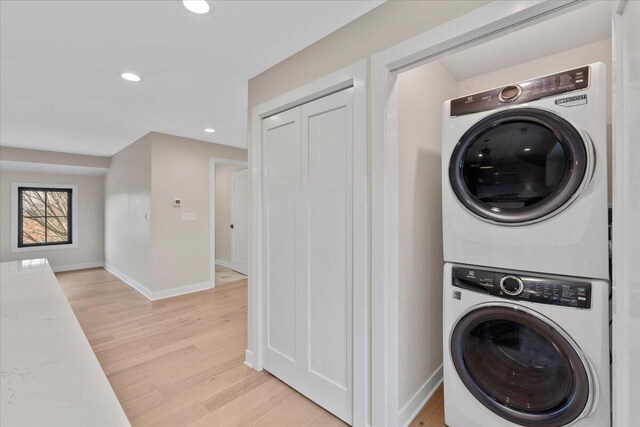 laundry room featuring recessed lighting, laundry area, stacked washer / dryer, baseboards, and light wood-style floors