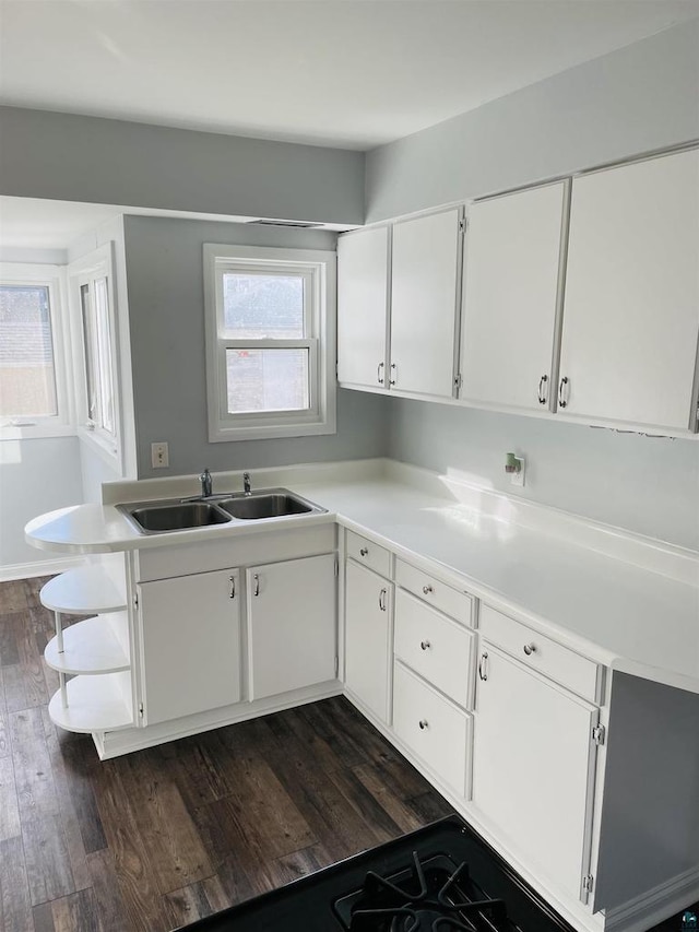 kitchen with dark wood-type flooring, sink, kitchen peninsula, and white cabinets