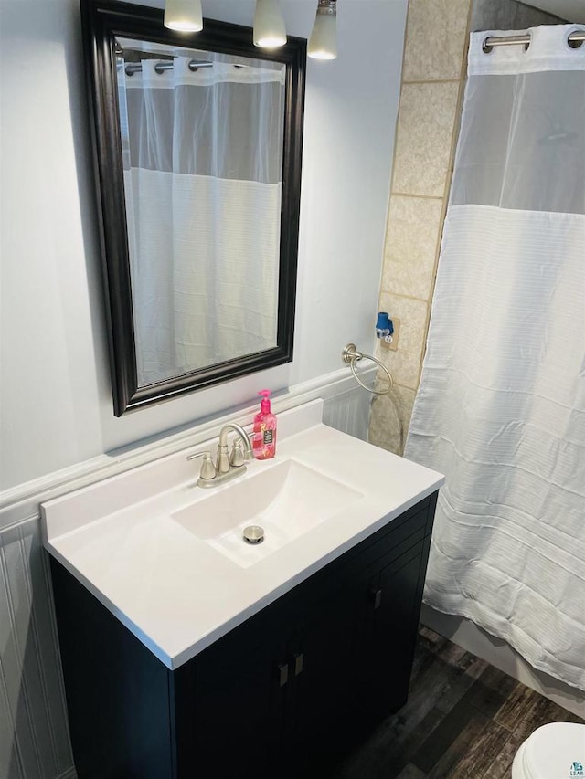 bathroom with vanity, toilet, wood-type flooring, and tile walls