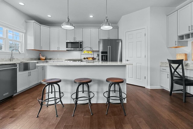 kitchen featuring a center island, appliances with stainless steel finishes, pendant lighting, and dark hardwood / wood-style floors