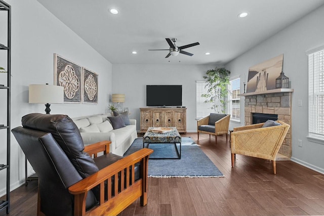 living room with dark wood-type flooring, ceiling fan, and a fireplace