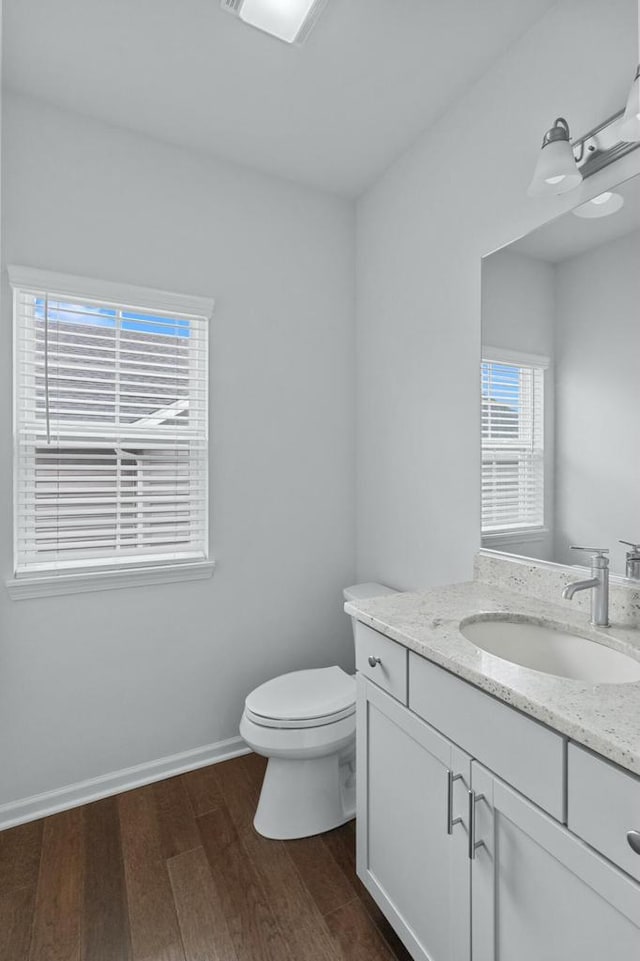 bathroom with a healthy amount of sunlight, vanity, hardwood / wood-style floors, and toilet