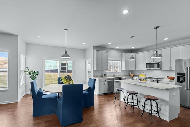 kitchen with dark wood-type flooring, a center island, hanging light fixtures, and stainless steel appliances