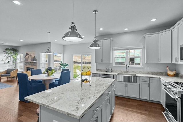 kitchen featuring a kitchen island, hardwood / wood-style flooring, high end range, a stone fireplace, and sink