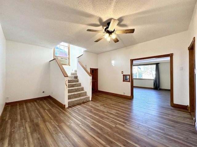 unfurnished living room featuring ceiling fan, a textured ceiling, and dark hardwood / wood-style floors