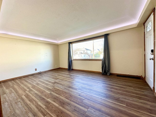 unfurnished room with a textured ceiling and wood-type flooring