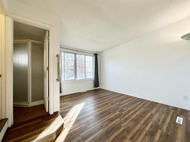 unfurnished room featuring a textured ceiling and dark hardwood / wood-style floors