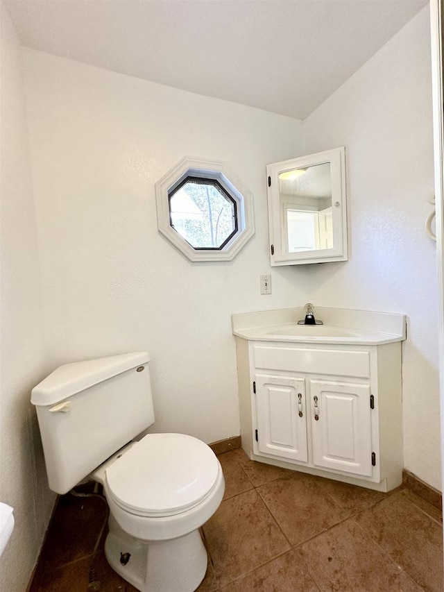 bathroom featuring vanity, toilet, tile patterned floors, and lofted ceiling