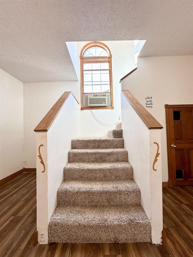 staircase with cooling unit, hardwood / wood-style floors, and a textured ceiling