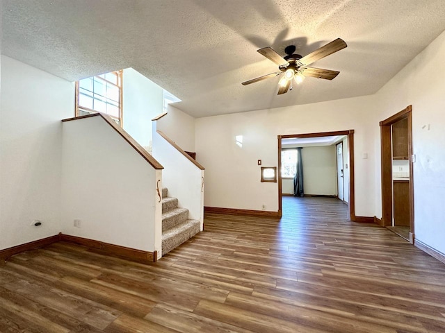 unfurnished living room featuring ceiling fan, a textured ceiling, and dark hardwood / wood-style flooring