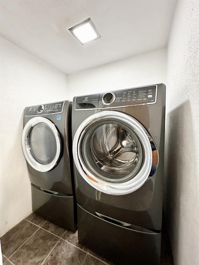 laundry area featuring dark tile patterned floors and washing machine and clothes dryer