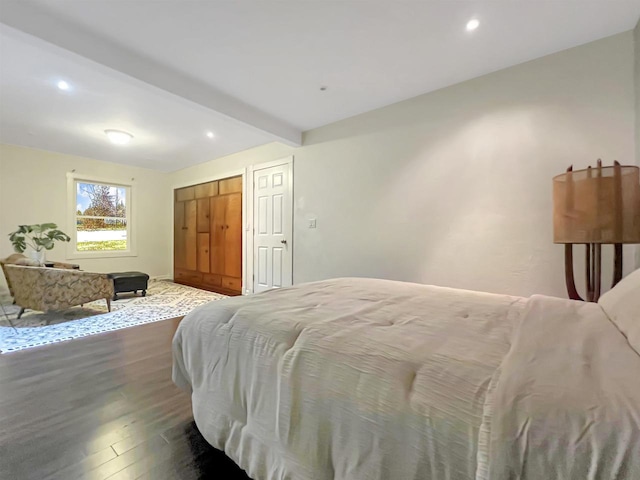 bedroom with a closet, beam ceiling, and hardwood / wood-style flooring