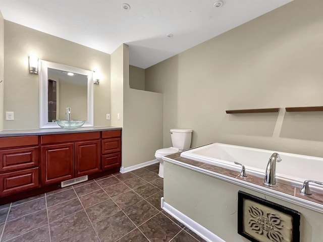 bathroom featuring vanity, toilet, tile patterned floors, and a washtub