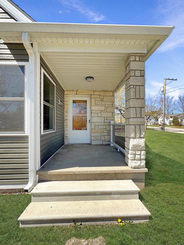 view of exterior entry with covered porch and a yard