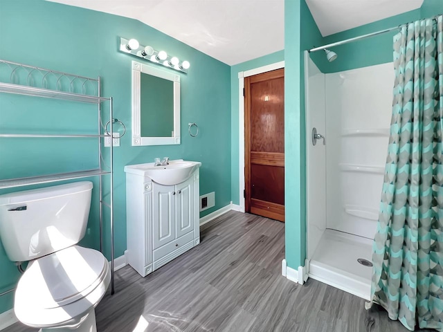 bathroom with curtained shower, toilet, vaulted ceiling, vanity, and hardwood / wood-style flooring