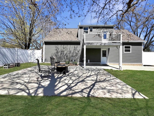 back of house with a patio area, an outdoor fire pit, a lawn, and a balcony