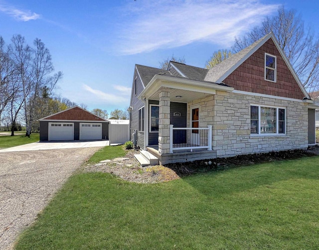 view of front of home with a porch, a front lawn, an outbuilding, and a garage